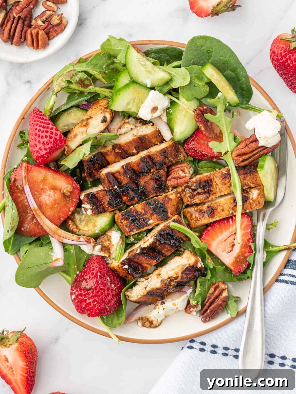 A serving plate of strawberry balsamic chicken salad with a fork.