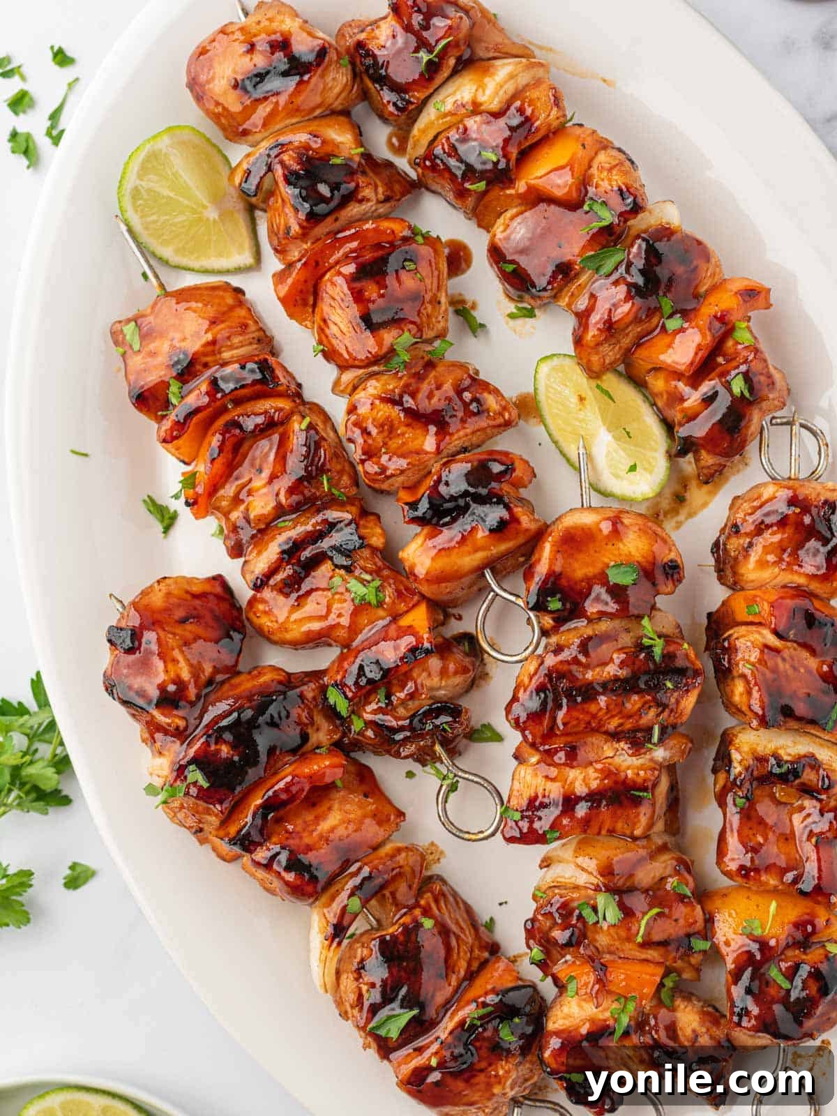The Ultimate BBQ Chicken Skewers 7 A beautifully arranged platter of cooked BBQ chicken skewers, garnished with fresh parsley and lime wedges, ready for serving.