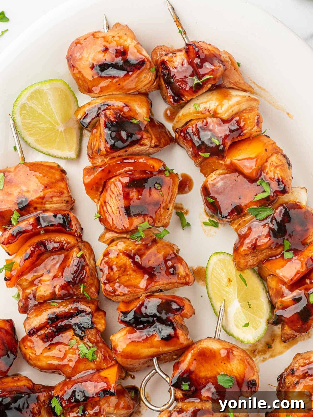 The Ultimate BBQ Chicken Skewers 8 A vibrant platter of cooked honey BBQ chicken kabobs, beautifully garnished with fresh parsley and zesty lime wedges.