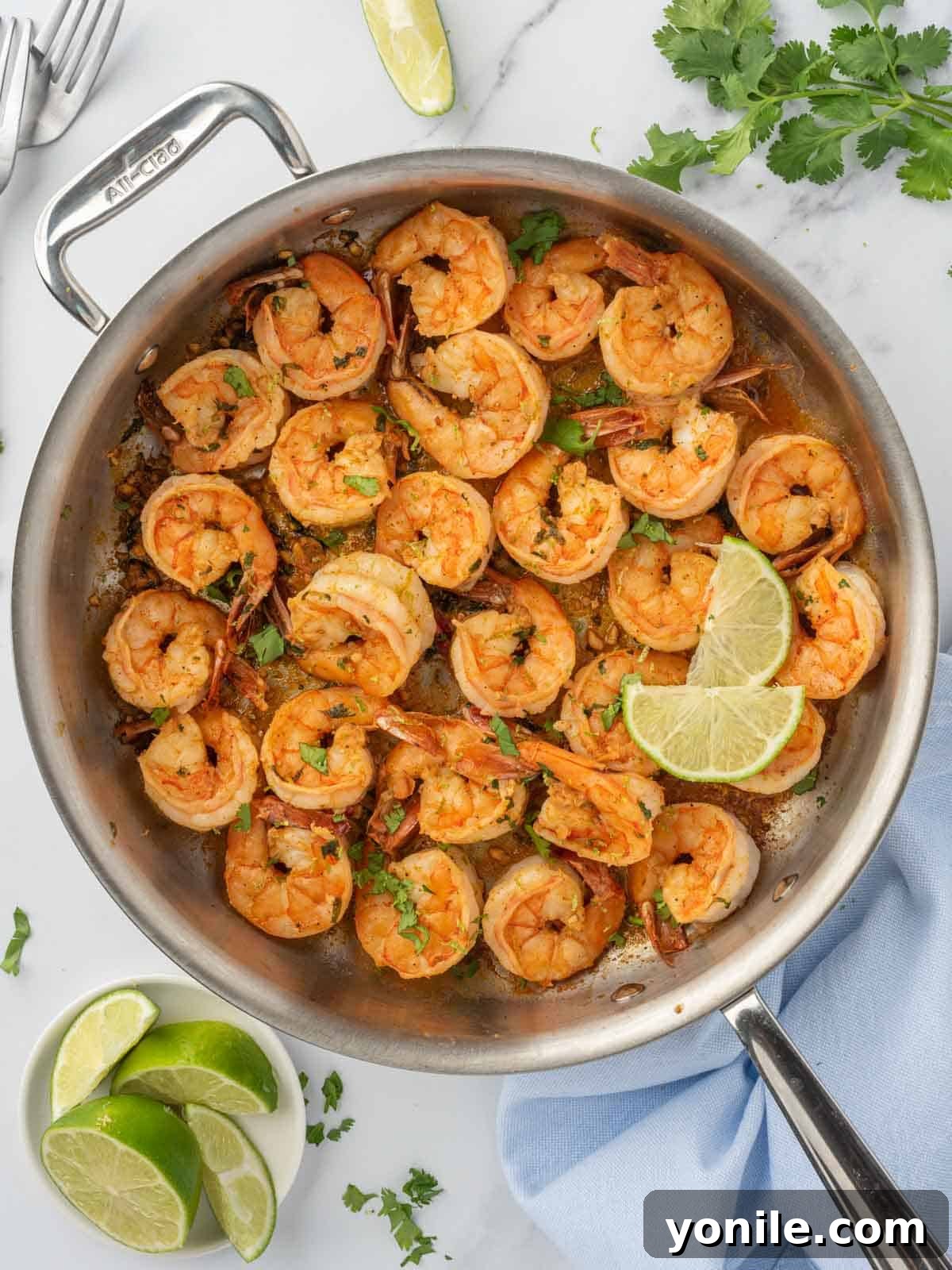 Freshly cooked Chili Lime Shrimp garnished with cilantro and lime wedges in a cast-iron skillet, ready to serve.