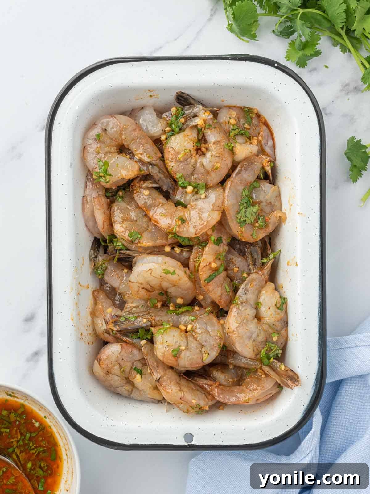 Jumbo shrimp marinating in a vibrant chili lime sauce in a bowl, infusing with flavor before cooking.