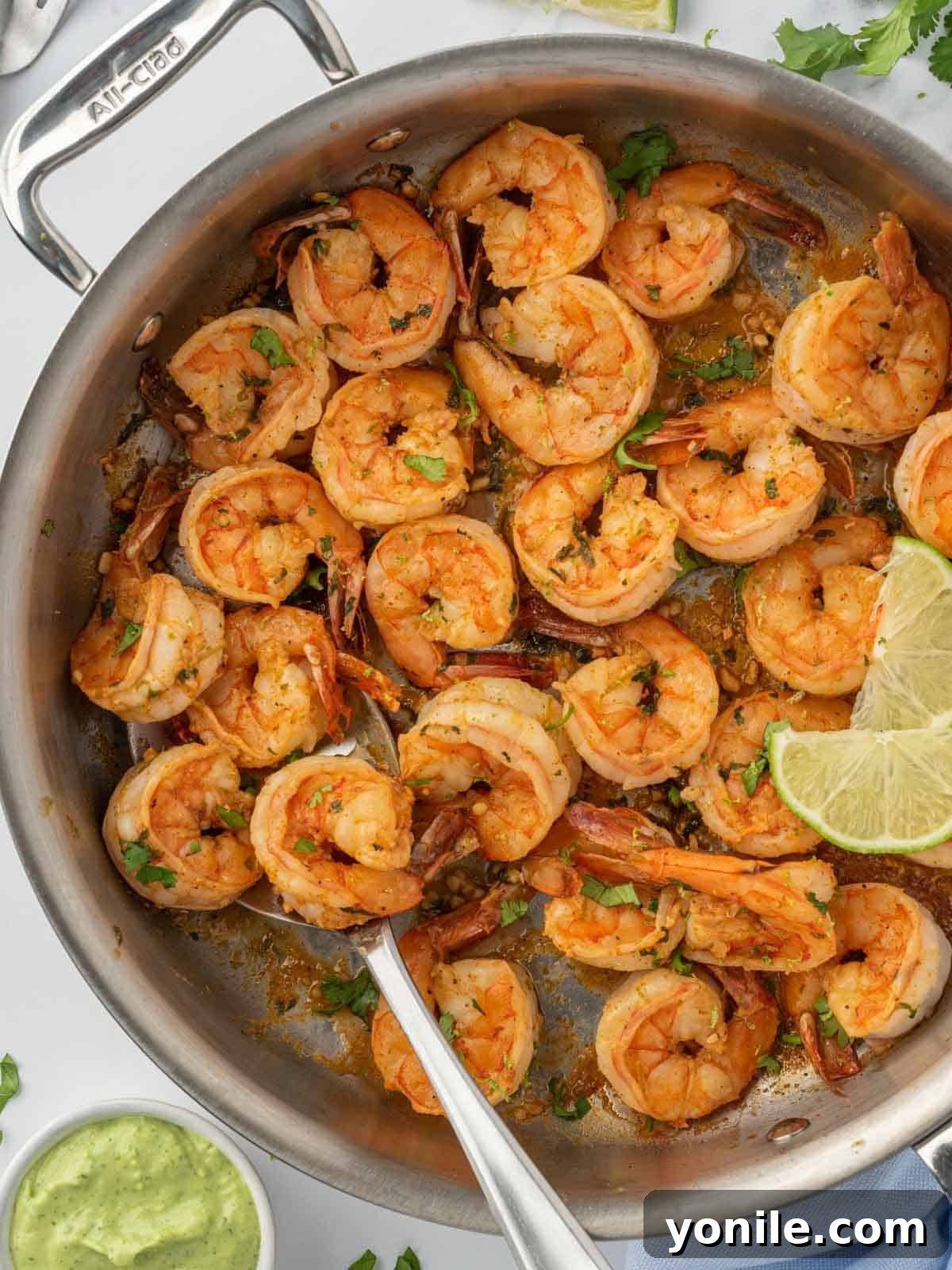 Chili powder seasoned shrimp being pan-seared in a hot skillet with cilantro and lime, creating a beautiful crust.