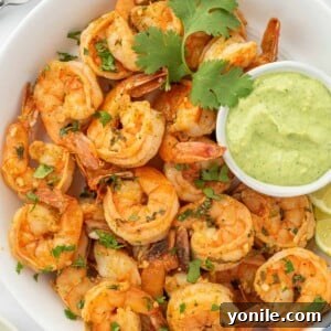 Chili lime shrimp in a serving bowl with green aioli for dipping.