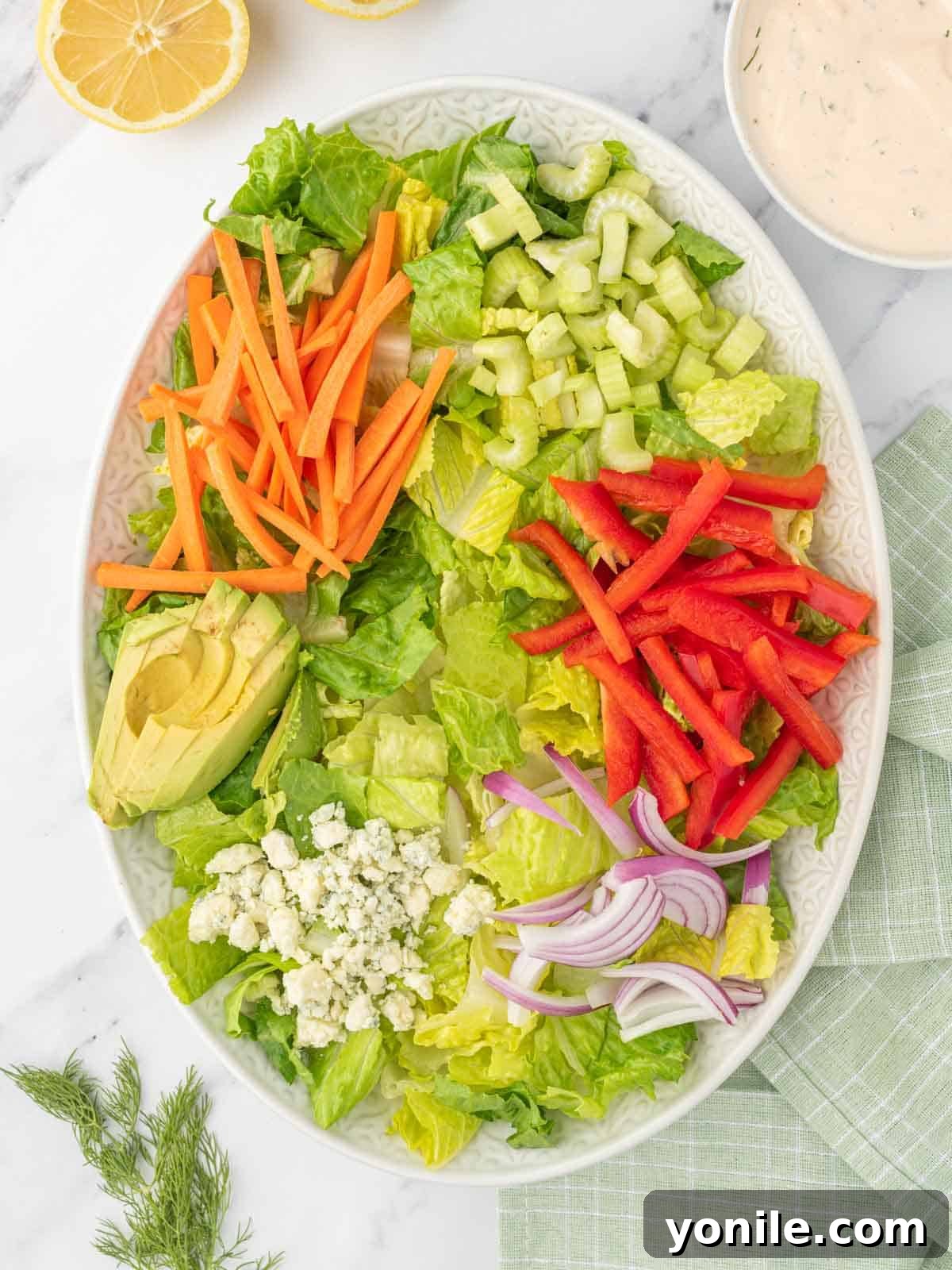 Assembling a vibrant buffalo chicken salad on a large platter.