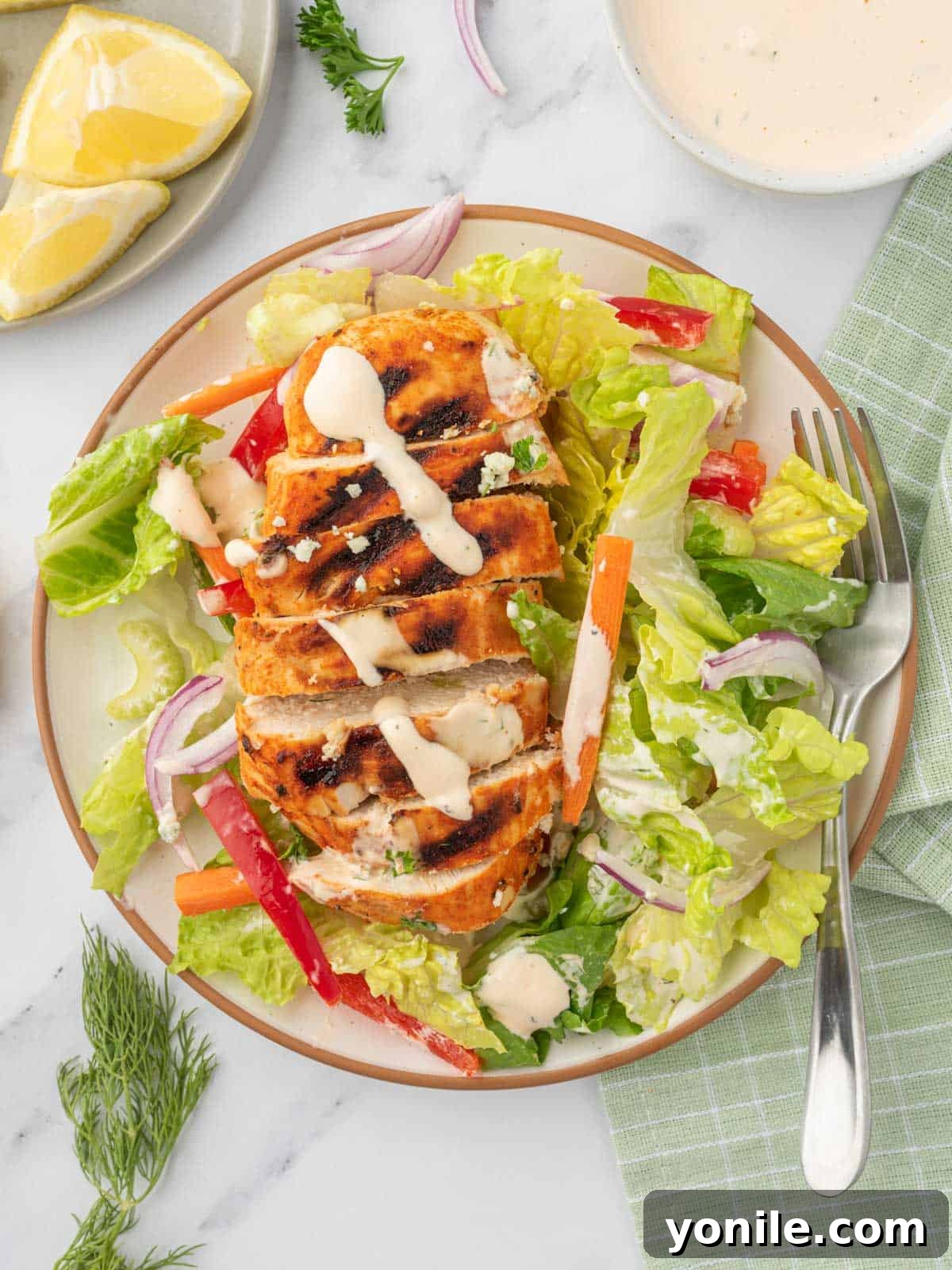 A single serving of grilled buffalo chicken salad presented beautifully on a plate with a fork.