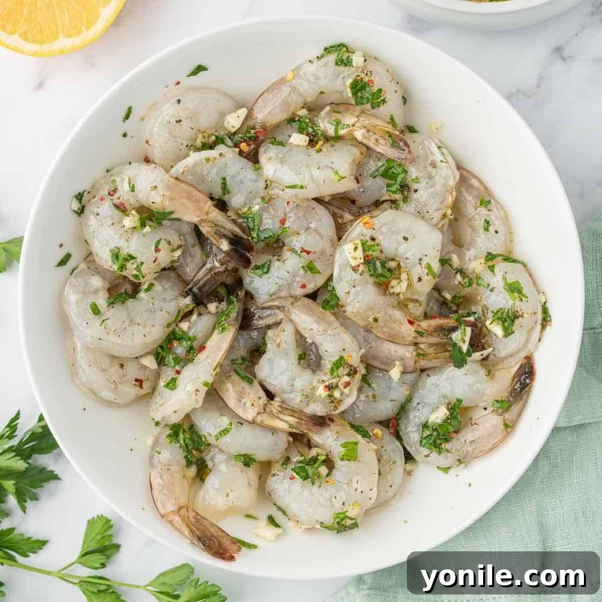 Raw shrimp soaking in a bowl of garlic citrus marinade, ready for grilling.