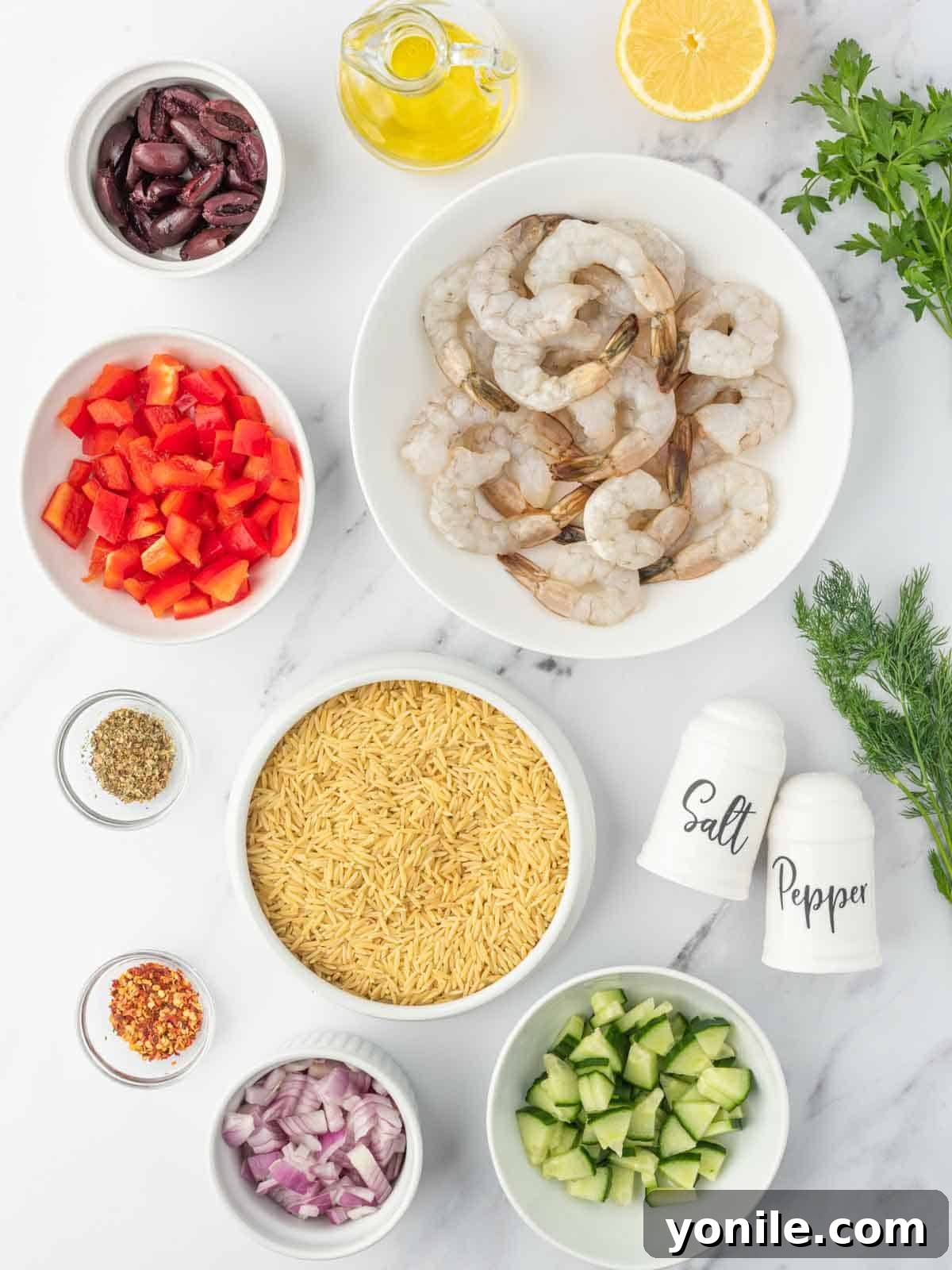 Mediterranean Shrimp Orzo Salad 3 A collection of fresh ingredients laid out, including shrimp, orzo, bell peppers, cucumber, red onion, kalamata olives, olive oil, lemon, and fresh herbs, ready for making shrimp orzo salad.