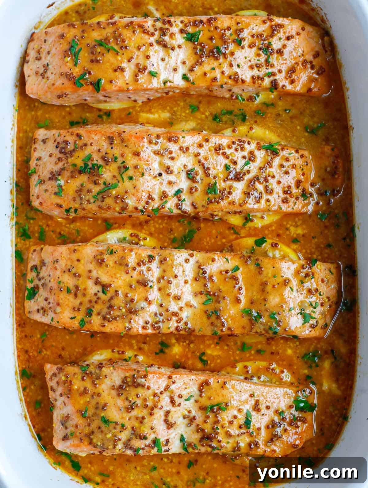 A baking dish with beautifully baked Dijon salmon, glistening with honey mustard sauce.