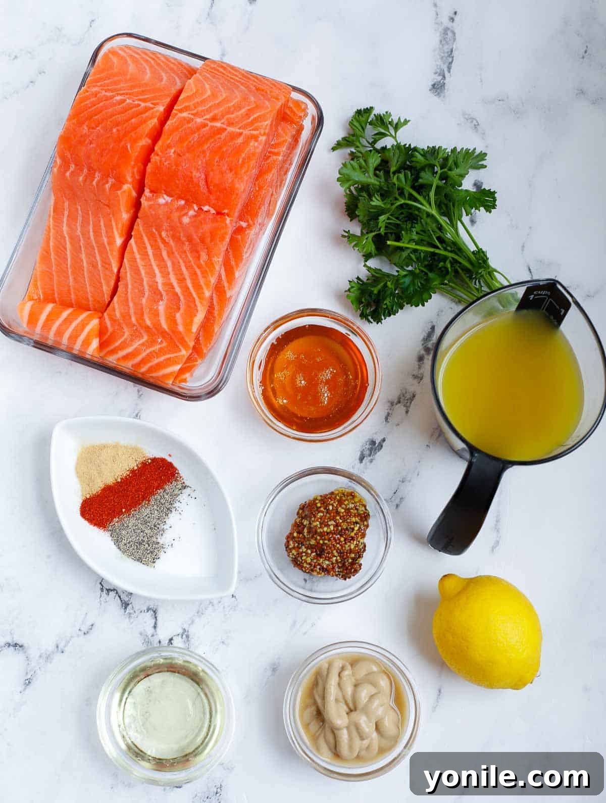 A selection of fresh ingredients laid out for baked honey mustard salmon, including salmon fillets, lemons, honey, and various mustards.