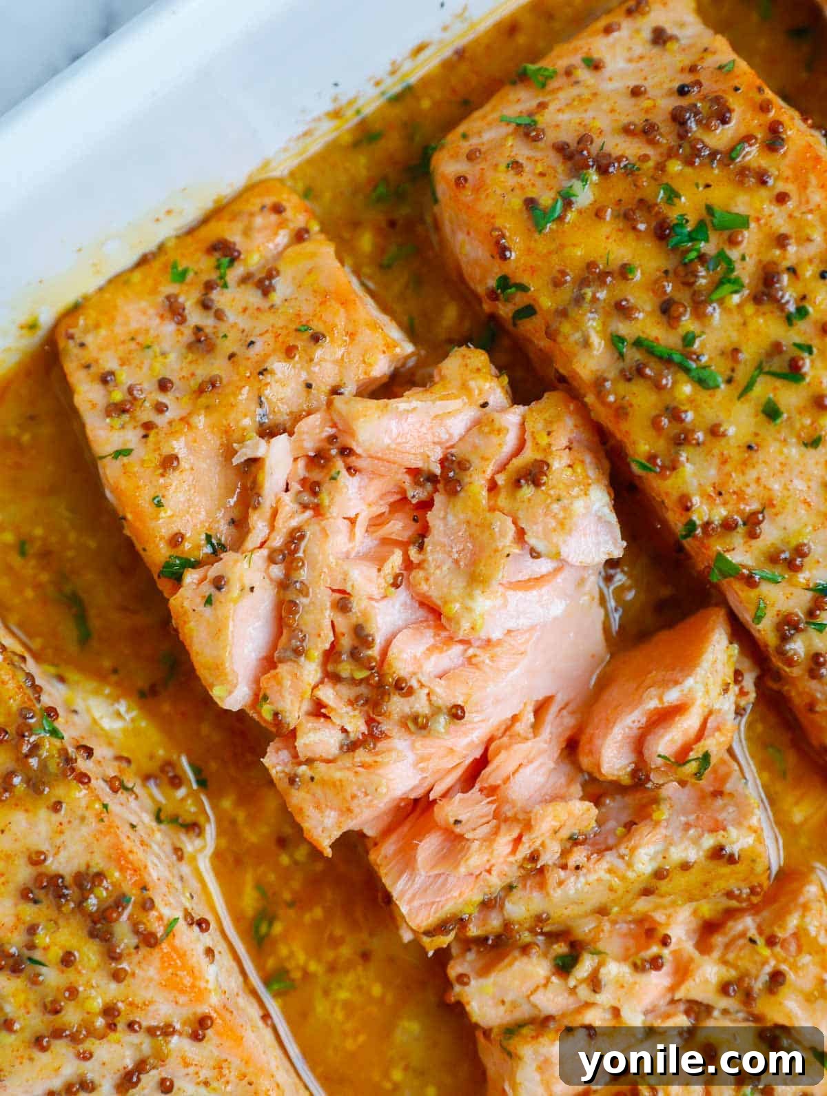 A final close-up of a serving of flaky baked Dijon salmon, highlighted by the honey mustard glaze.