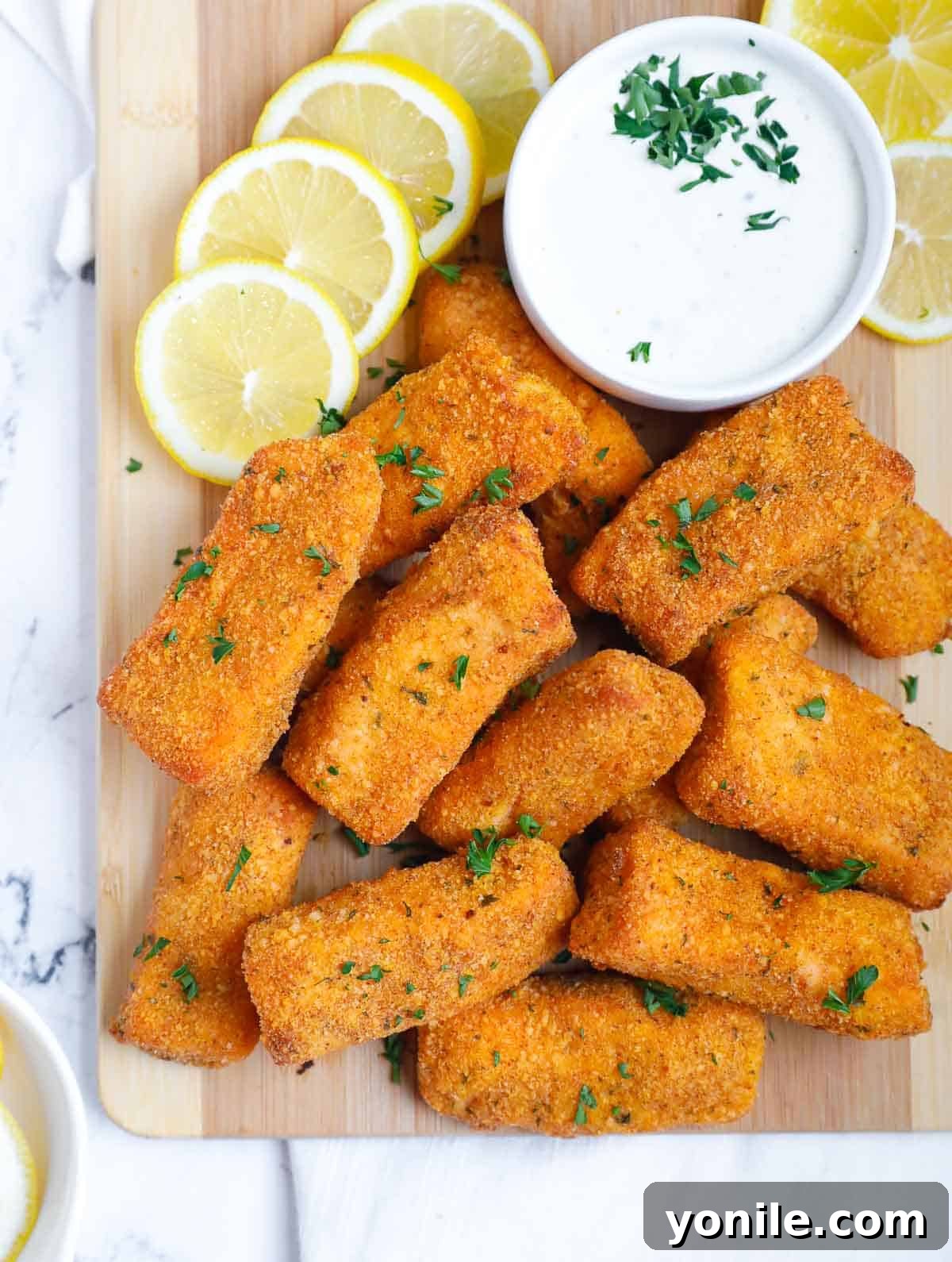 Golden-brown panko-crusted salmon fish sticks beautifully arranged on a wooden board, ready to be served.