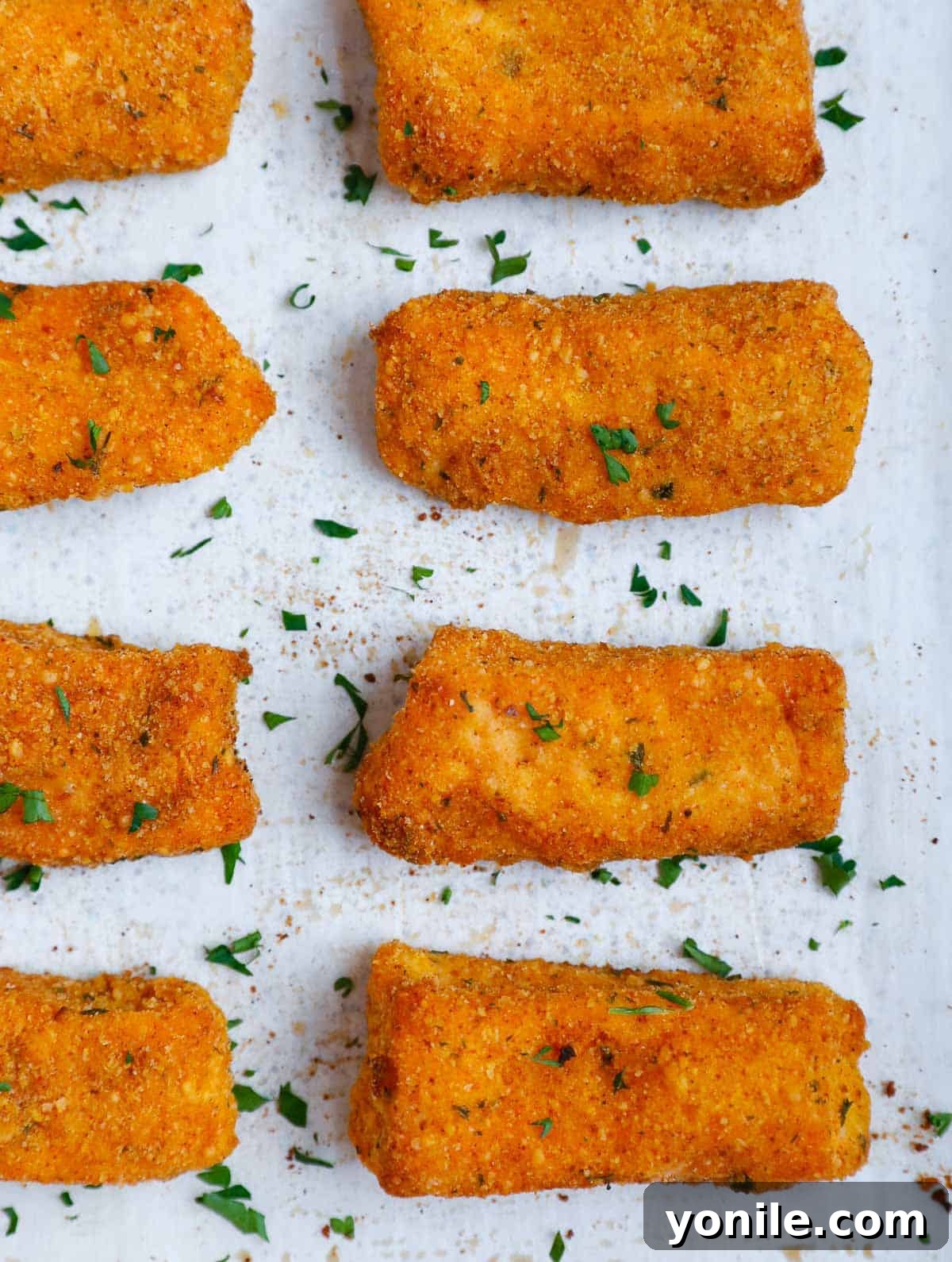A freshly baked tray of golden, crispy salmon fish sticks, hot out of the oven and looking delicious.