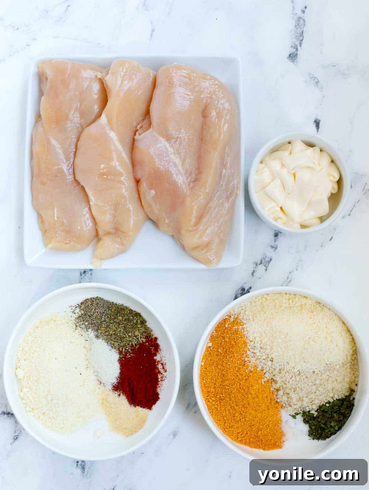All the fresh and pantry ingredients laid out for preparing oven baked chicken cutlets.