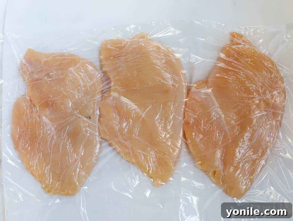 Pounding boneless, skinless chicken breasts to an even thickness for uniform cooking.