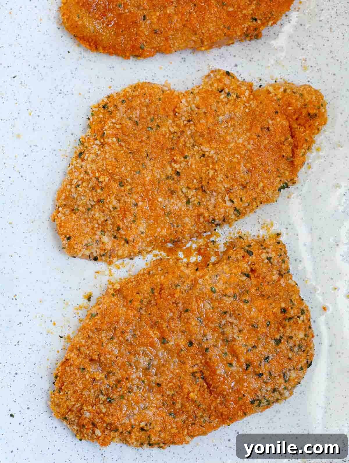 Freshly baked chicken cutlets, golden and crispy, ready for garnishing with parsley.