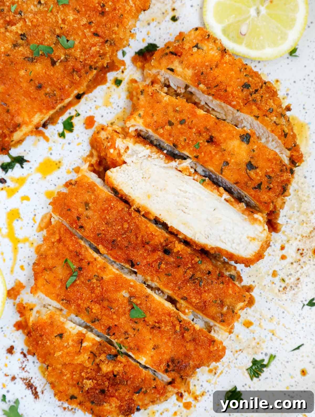 A perfectly sliced panko crusted chicken cutlet, revealing its juicy interior, ready for serving.