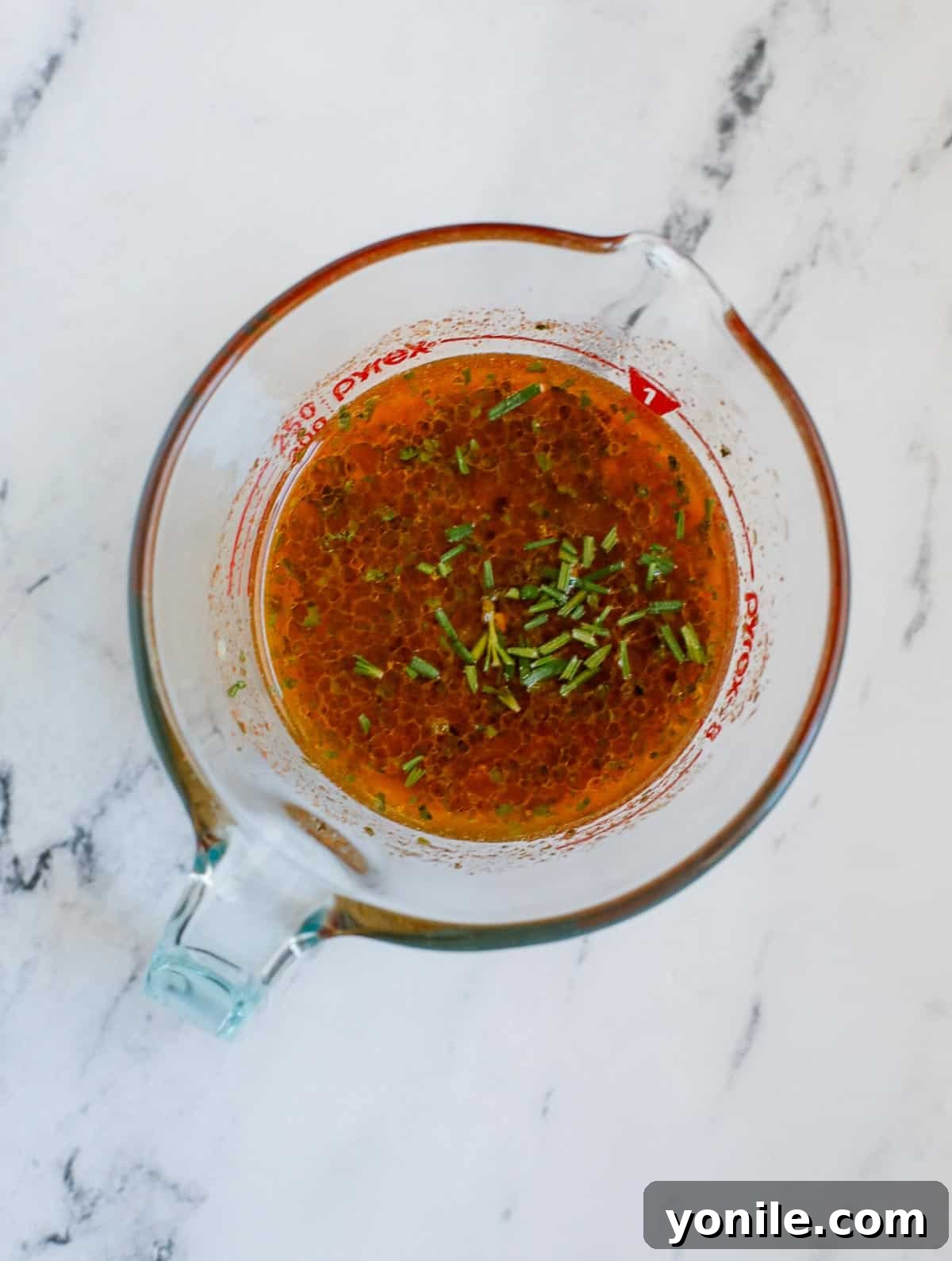 A bowl filled with the vibrant, golden lemon rosemary sauce ingredients, ready to be mixed.