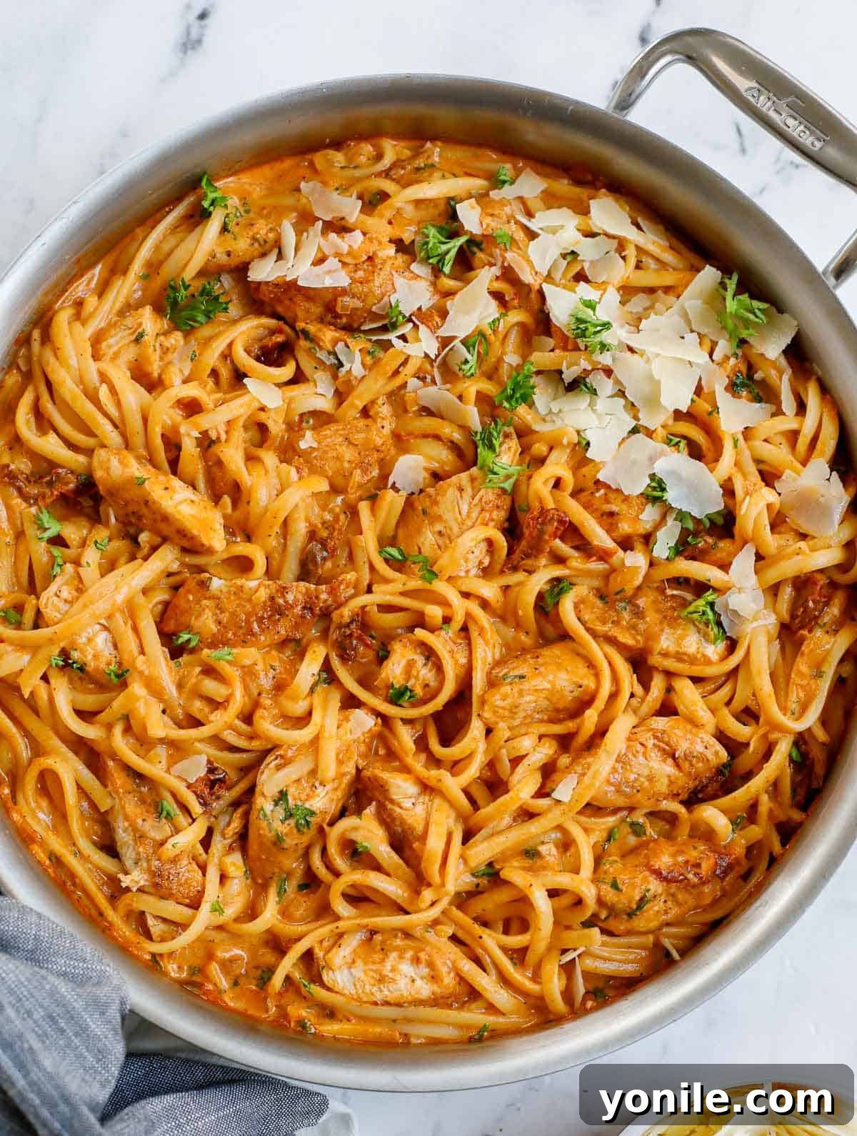 A skillet of creamy spicy chicken pasta, garnished with fresh parsley.
