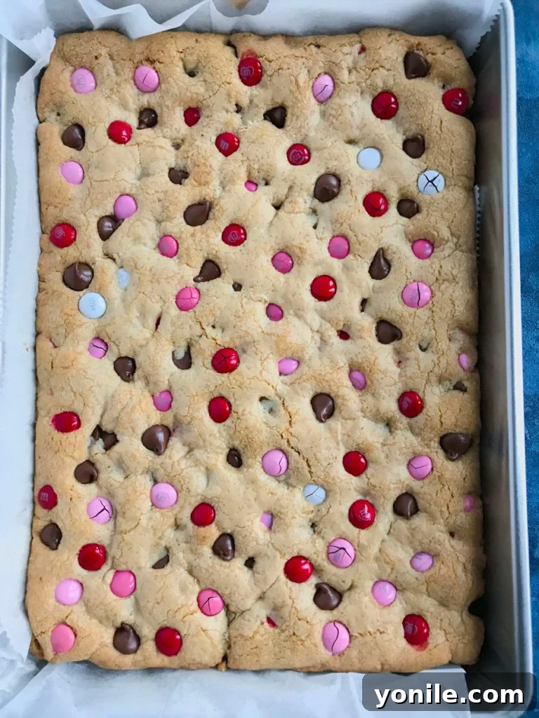 Unbaked Valentine's M&M Chocolate Chip Cookie Bars dough spread in a baking pan.