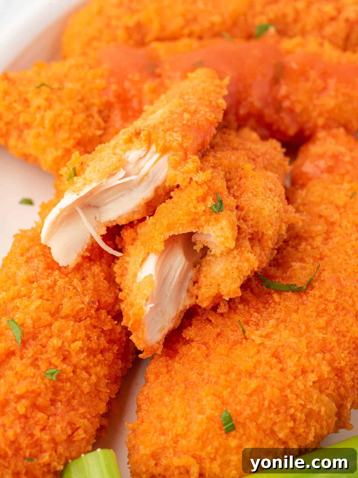 Oven-Crisped Buffalo Tenders 8 A close-up of a single juicy piece of buffalo chicken tender, showing its crispy texture and sauce.