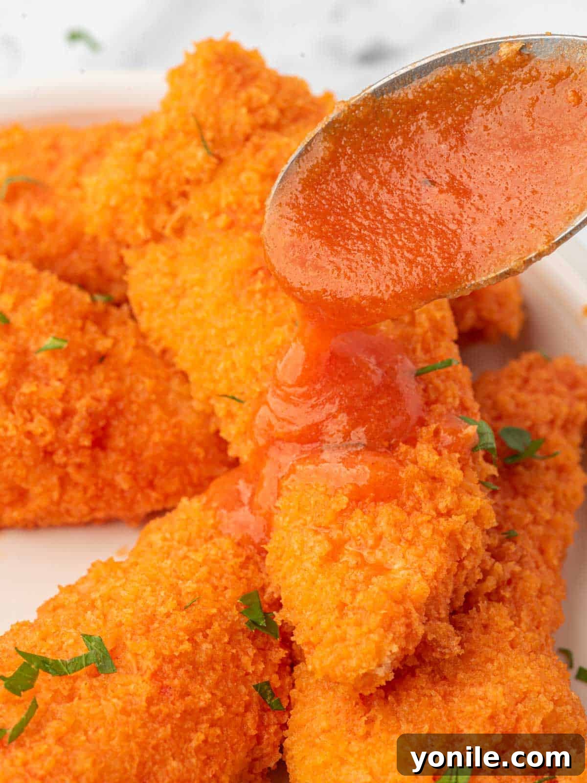 Oven-Crisped Buffalo Tenders 9 Buffalo sauce drizzled over a freshly baked plate of crispy chicken tenders.