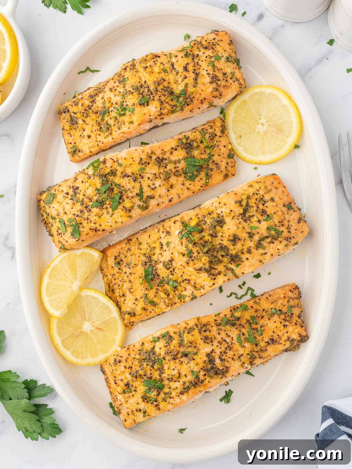 Lemon pepper baked salmon on a platter garnished with lemon slices.
