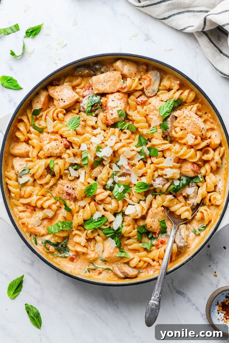 creamy mushroom chicken pasta in a skillet garnished with basil