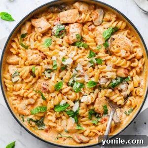 creamy mushroom chicken pasta in a skillet garnished with basil