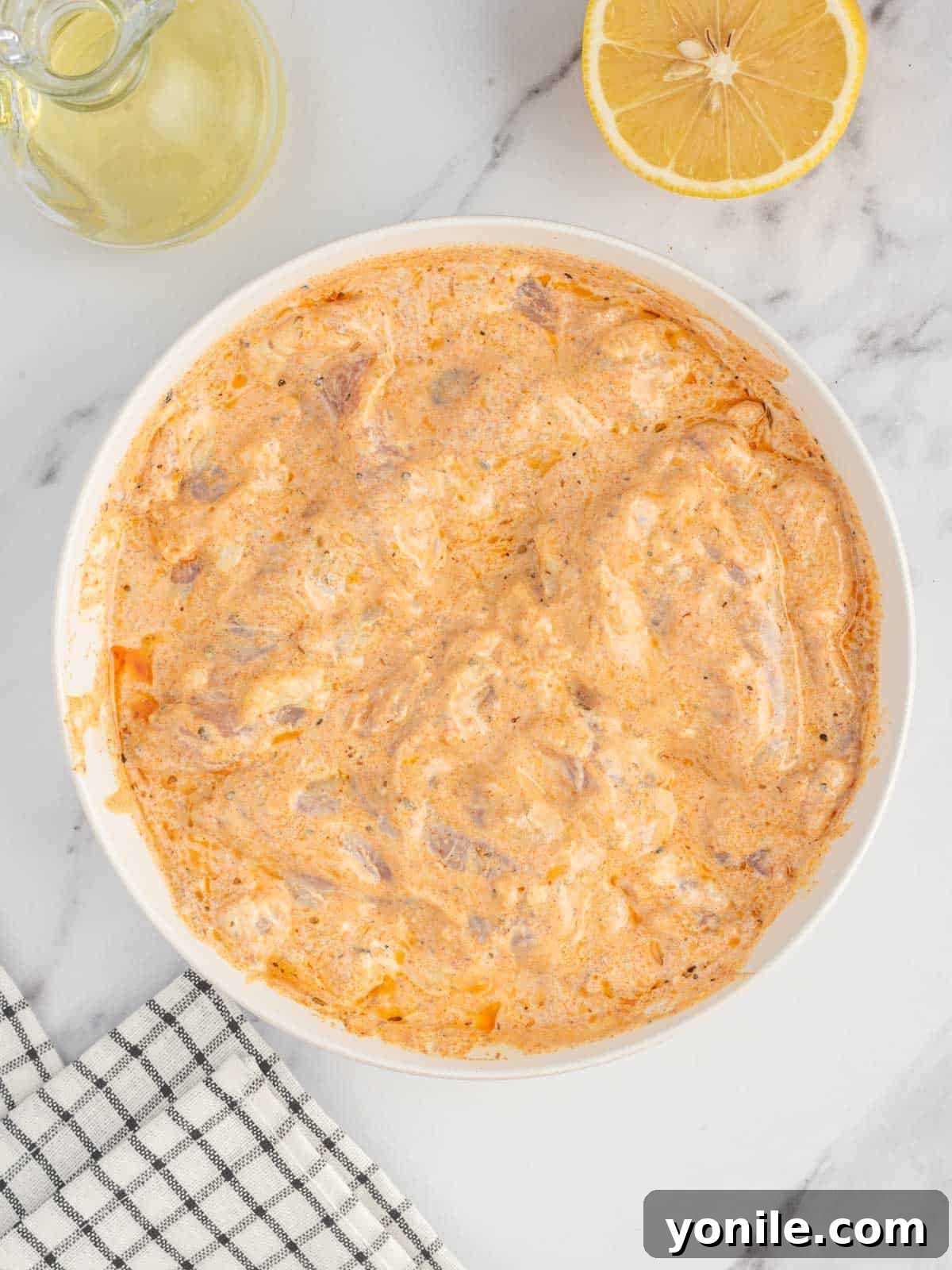 Authentic Homemade Greek Chicken Gyros 4 Chicken thighs marinating in a bowl with Greek yogurt, lemon, garlic, and herbs, ready for authentic chicken gyros.