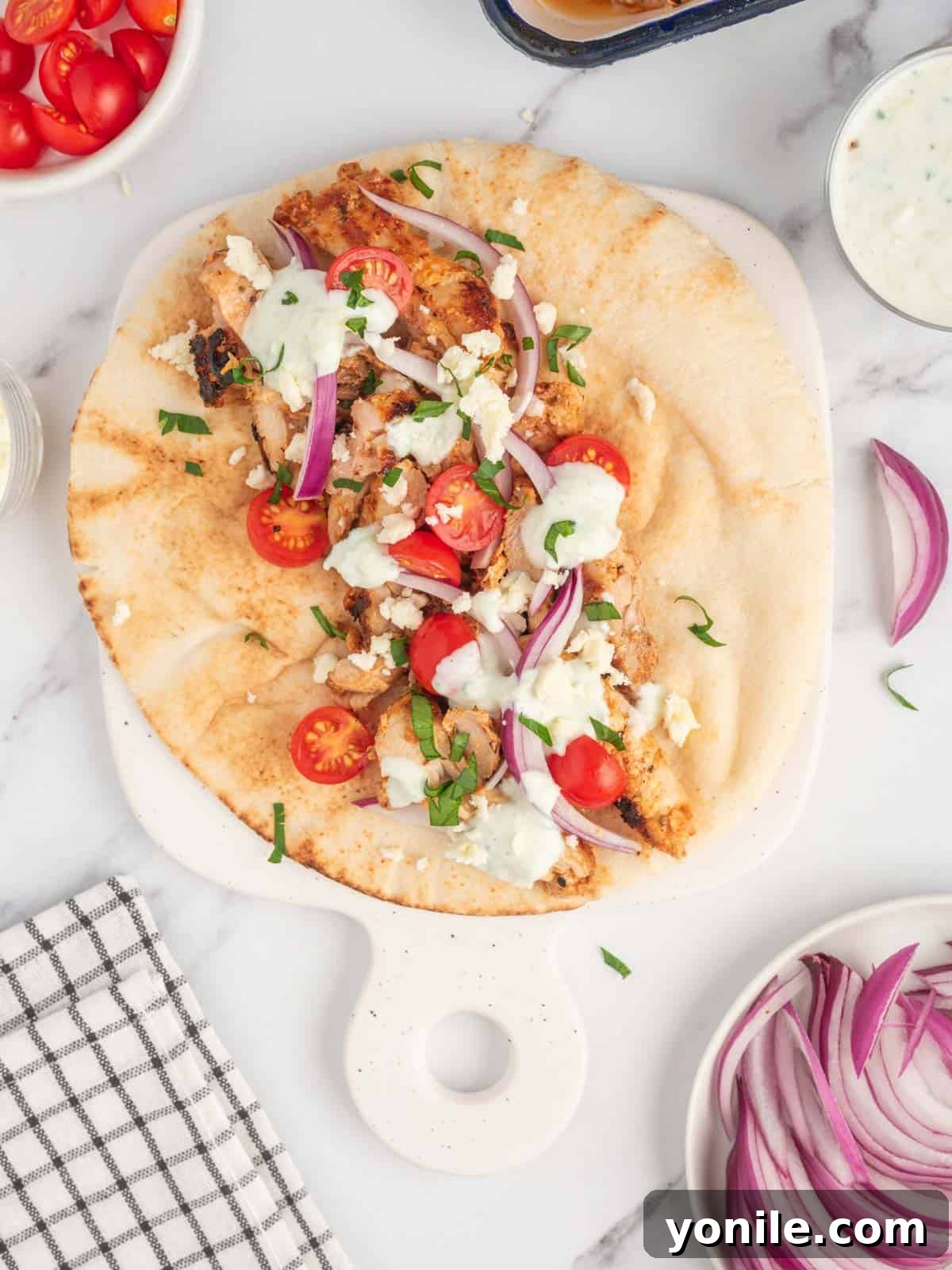 Authentic Homemade Greek Chicken Gyros 6 A platter filled with freshly assembled homemade Greek chicken gyros, garnished with herbs and lemon wedges, ready to be served.