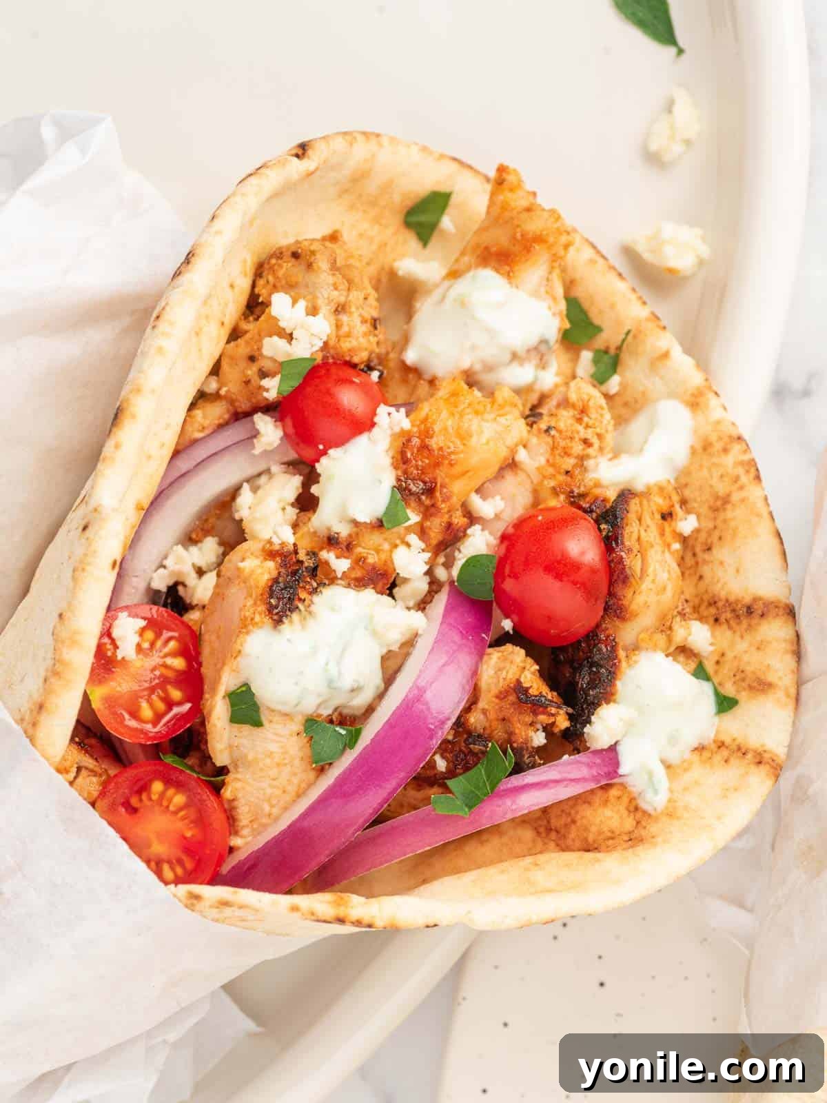 Authentic Homemade Greek Chicken Gyros 8 Close-up view of a generously filled Greek Chicken Gyro, showcasing the tender chicken, fresh toppings, and creamy Tzatziki Sauce, ready for a delicious bite.
