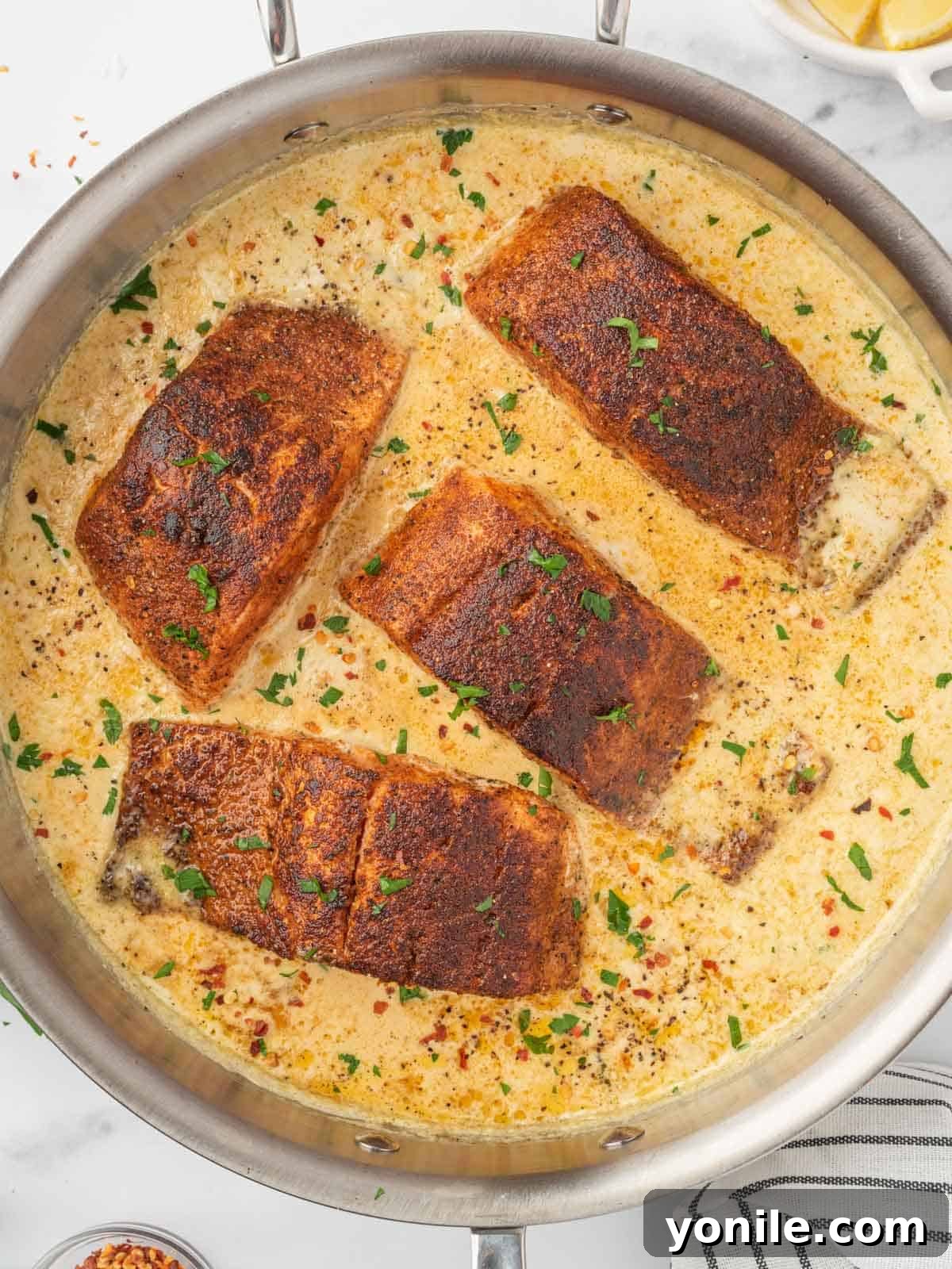 Salmon bathed in creamy sauce in a skillet, ready to serve.