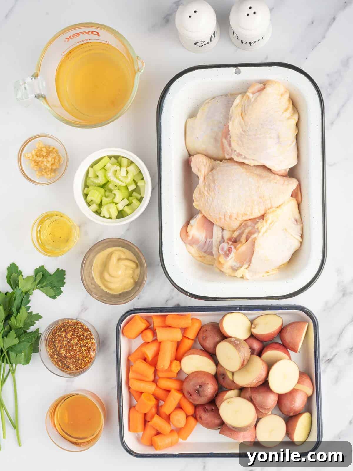 A flat lay of fresh ingredients laid out for Instant Pot Chicken Stew, including chicken thighs, various mustards, honey, potatoes, and carrots.