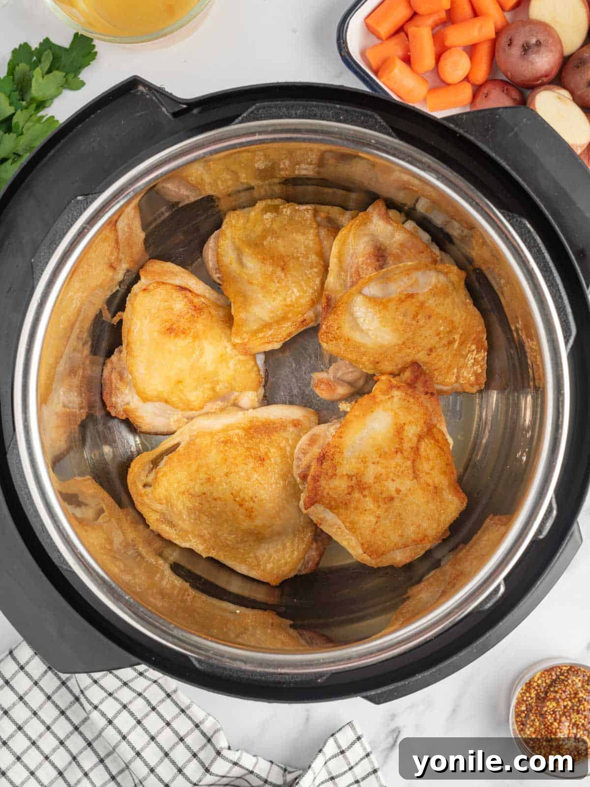 Raw chicken thighs being seared skin-side down in an Instant Pot, showing a golden brown crust forming.