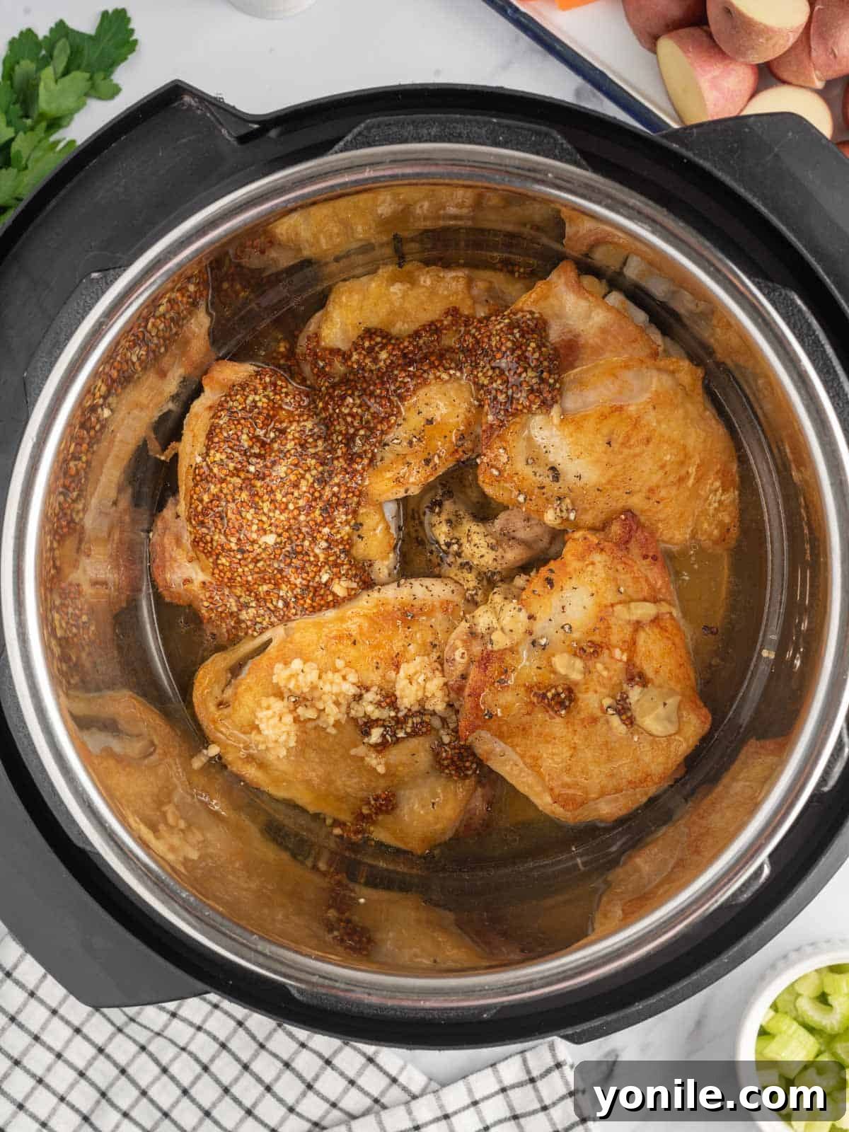 Seared chicken thighs in the Instant Pot, with honey mustard sauce being poured over them.