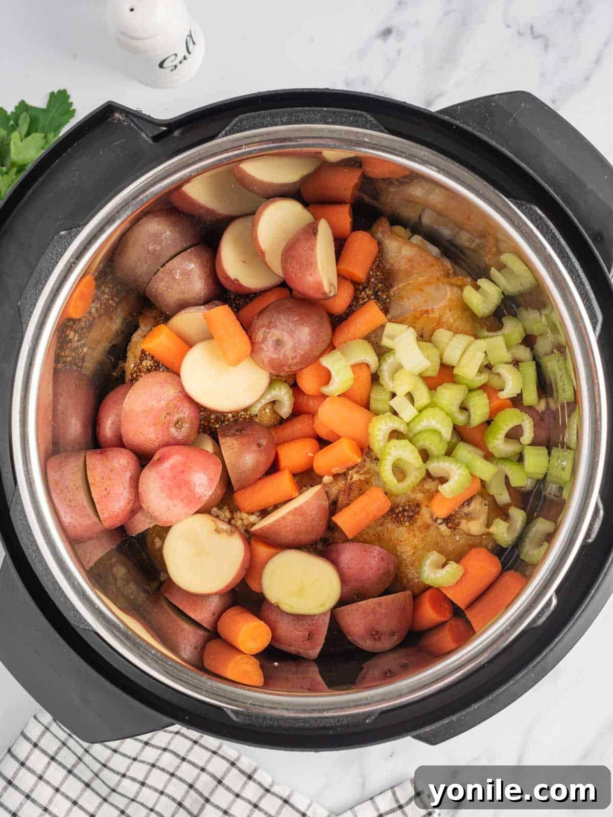 Halved baby potatoes, carrots, and sliced celery added to the Instant Pot with seared chicken thighs and honey mustard sauce.