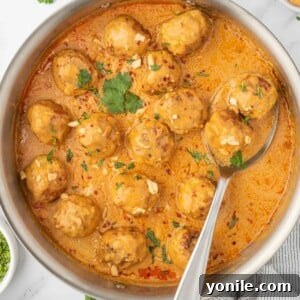 Meatballs in a skillet with coconut curry sauce.