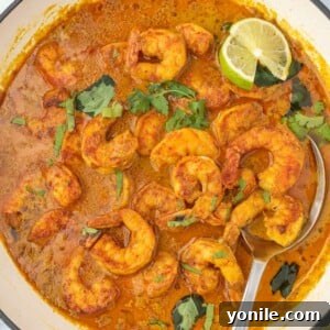 Vibrant Thai Coconut Shrimp Curry 10 A pot of red curry shrimp with a spoon, highlighting the rich sauce and tender shrimp.