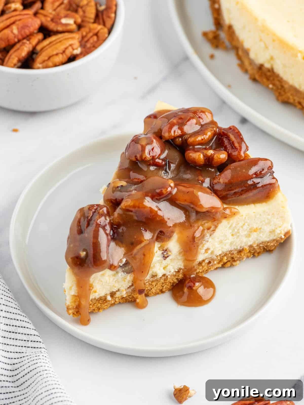 A perfectly portioned slice of caramel pecan cheesecake on a white plate, ready to be enjoyed.
