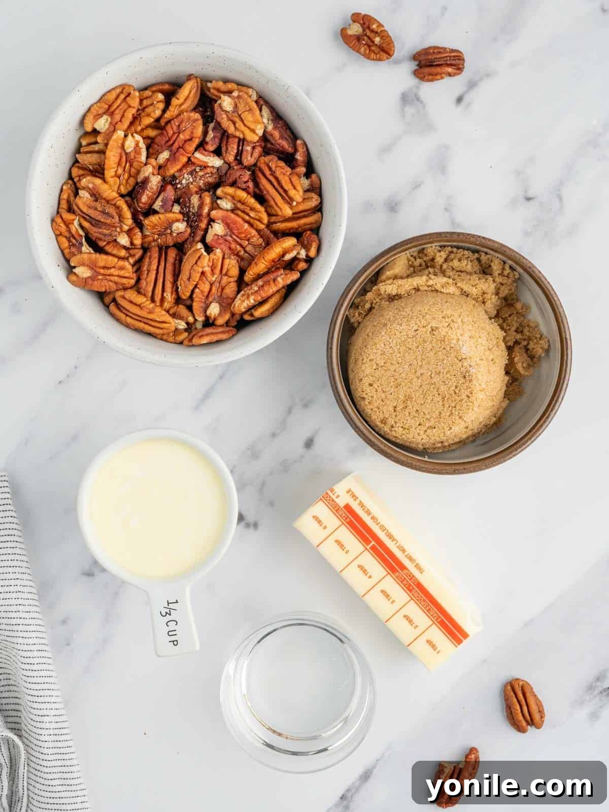 Assorted ingredients for the pecan topping, including brown sugar, butter, corn syrup, heavy cream, and pecan halves, ready for preparation.
