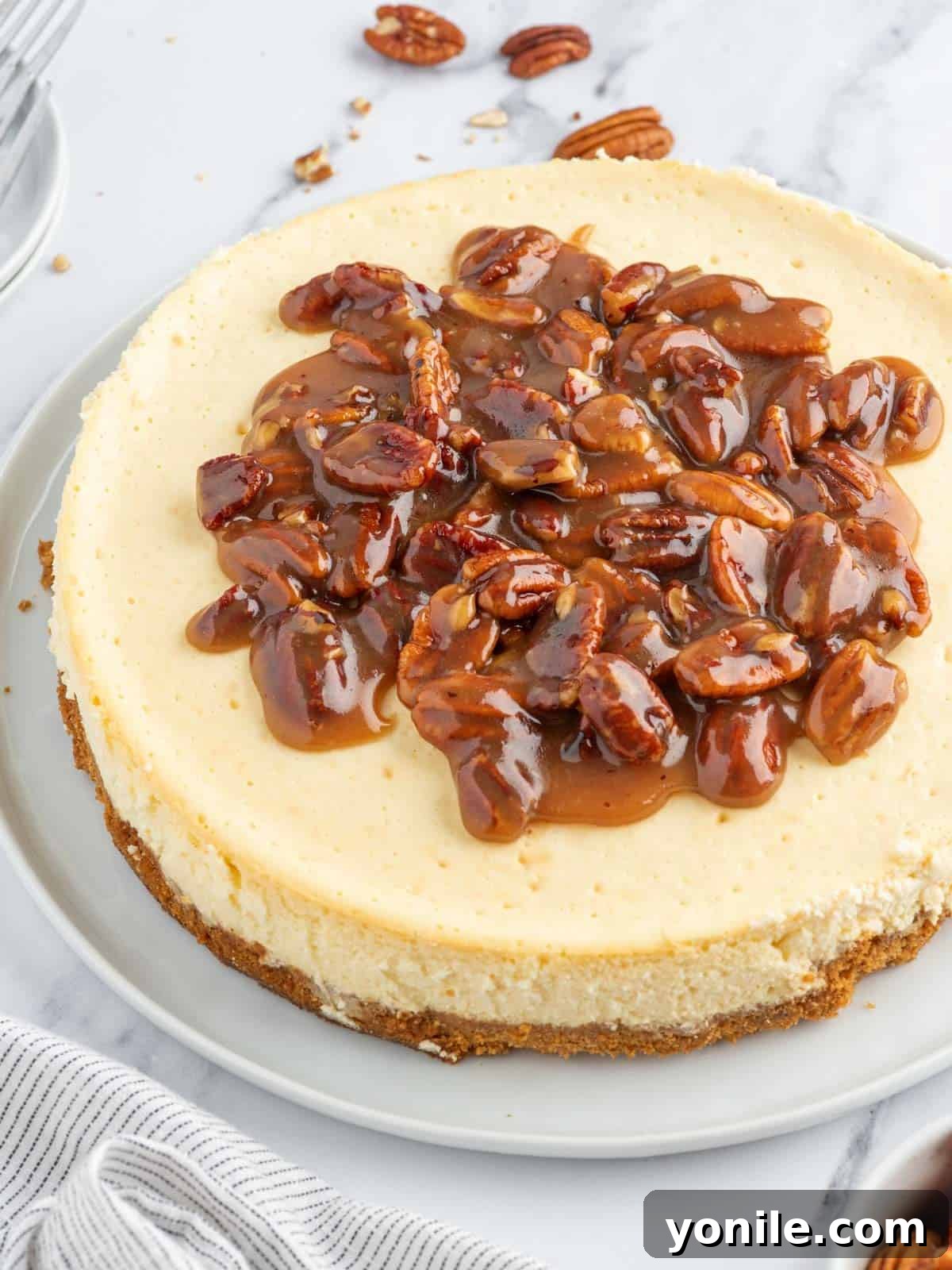 A whole pecan pie cheesecake sitting on an elegant platter, ready for serving at a festive gathering.