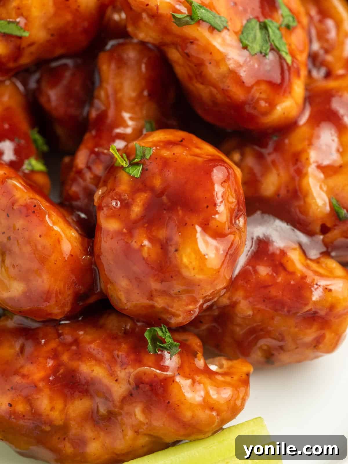 Close-up of an individual baked BBQ chicken bite, showcasing its glossy, sticky sauce and tender interior.