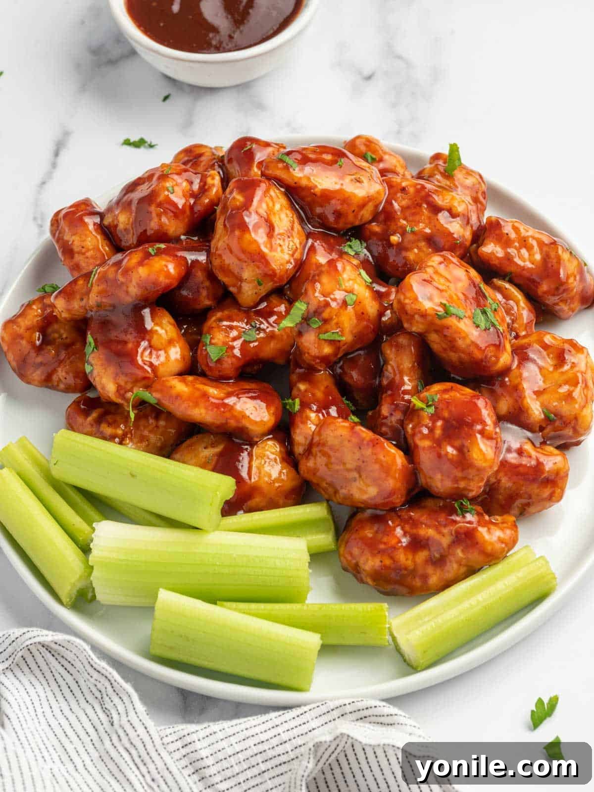 Baked BBQ chicken bites artfully arranged on a serving platter with fresh celery sticks.