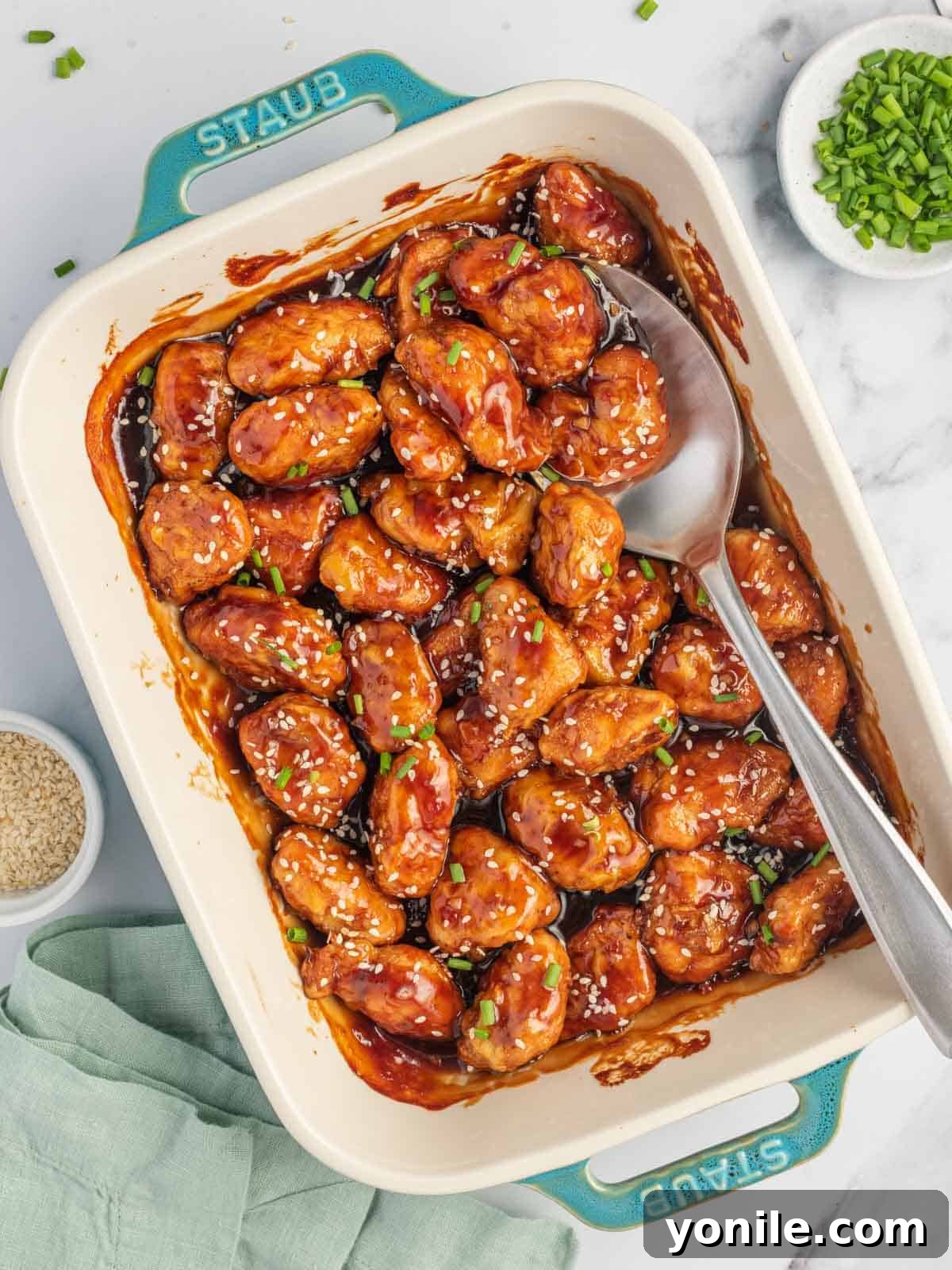 A casserole dish of asian chicken breast with sesame seeds.