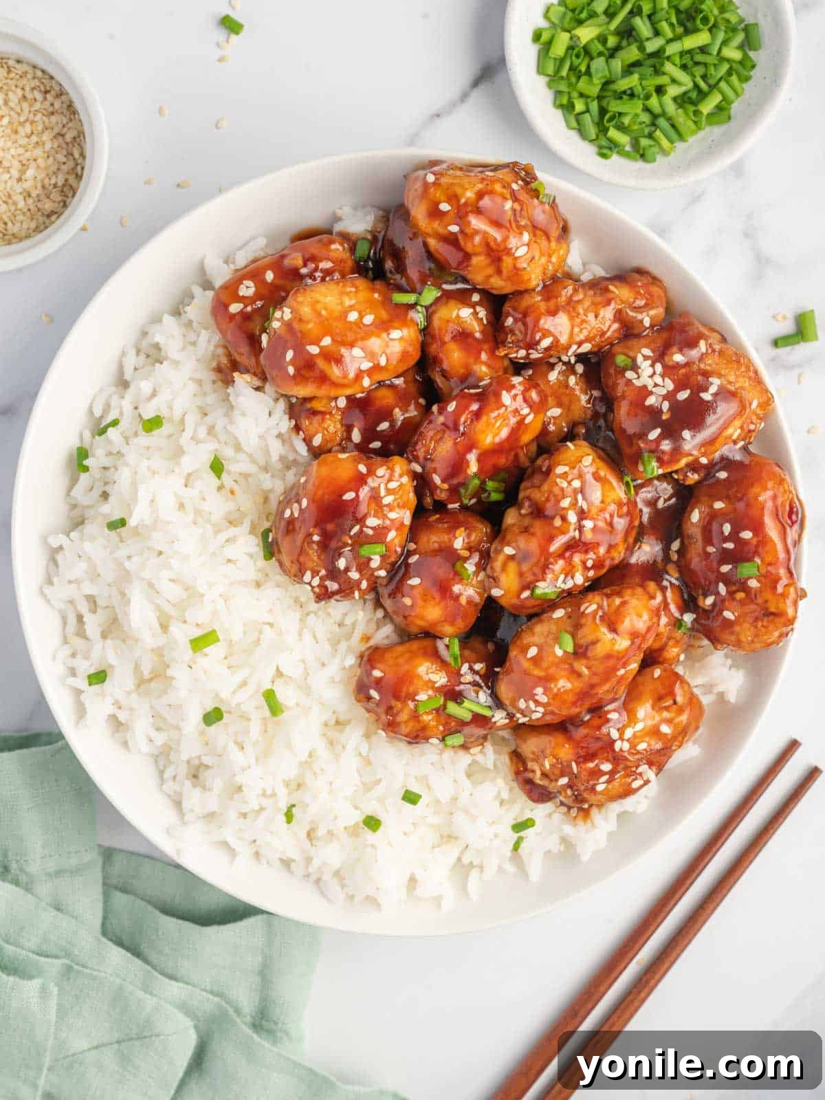 Baked honey sesame chicken on a plate with rice.