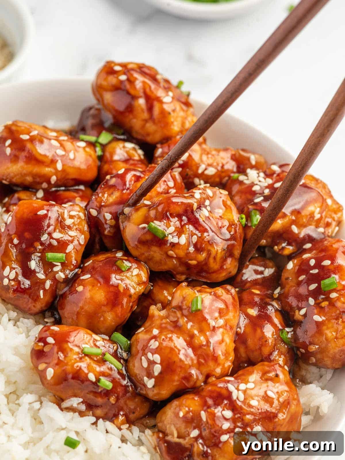 Chop sticks pick up a piece of baked asian chicken.