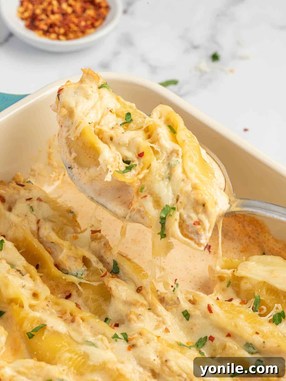 Spicy Cajun Chicken Alfredo Stuffed Pasta Shells 9 A close-up shot of a spoon lifting a perfect piece of Cajun Alfredo pasta, showing the creamy filling and sauce.