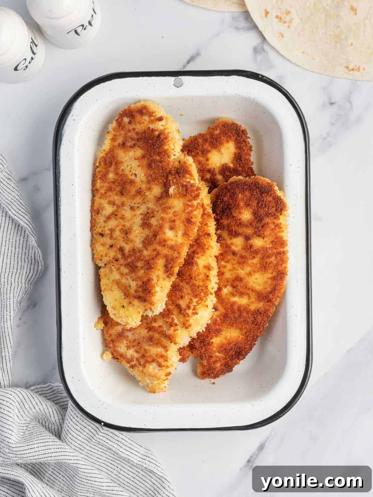 Homemade panfried chicken strips in a tray.