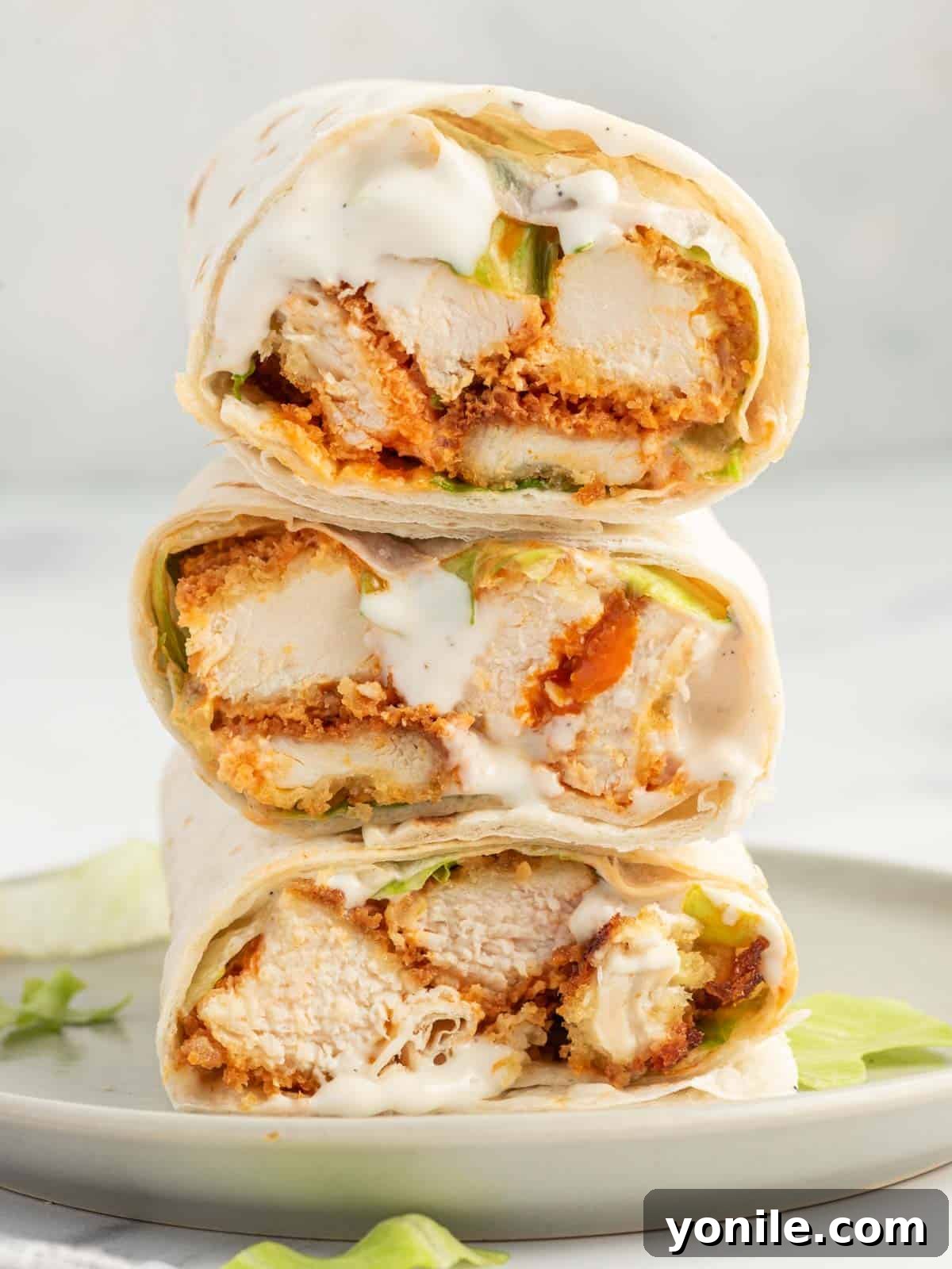 Crispy Buffalo chicken wrap sliced into pieces and stacked on a plate.