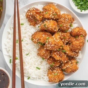 Chop sticks rest on a bowl of rice and vegan sesame cauliflower.